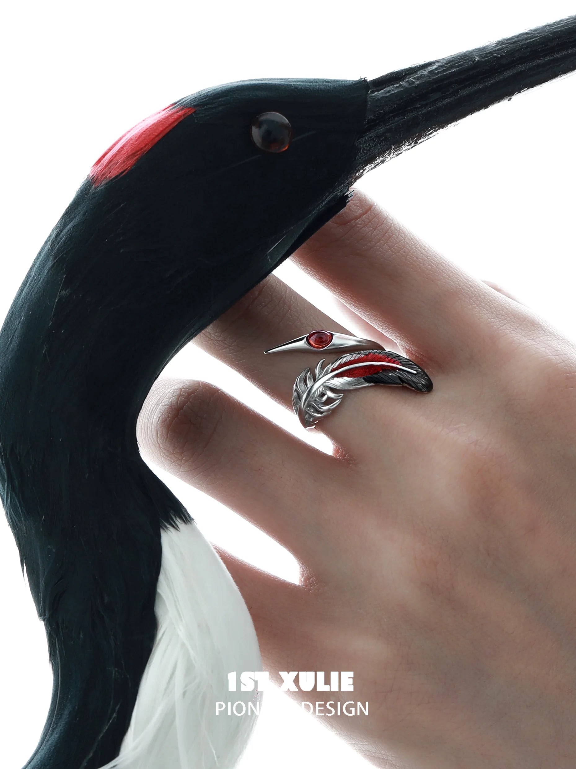 Gothic silver crane ring on a hand, featuring intricate design and red gemstone accents
