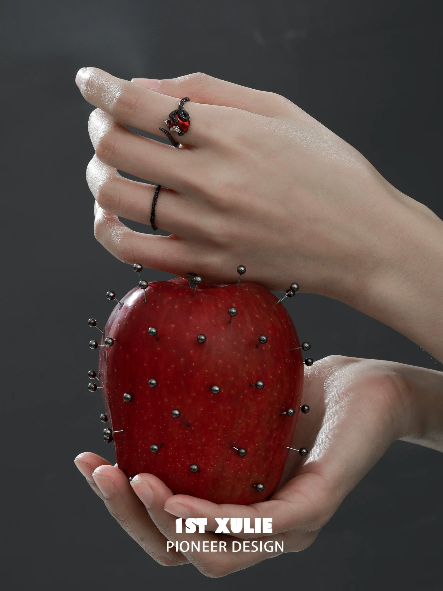 Gothic snake apple ring worn on hand holding an apple with pins for a striking contrast