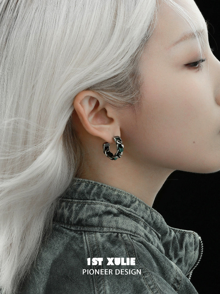 Gothic venomous spirit earrings displayed on a model with silver hair and a dark jacket