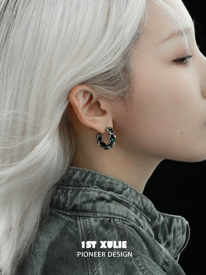 Gothic venomous spirit earrings displayed on a model with silver hair and a dark jacket