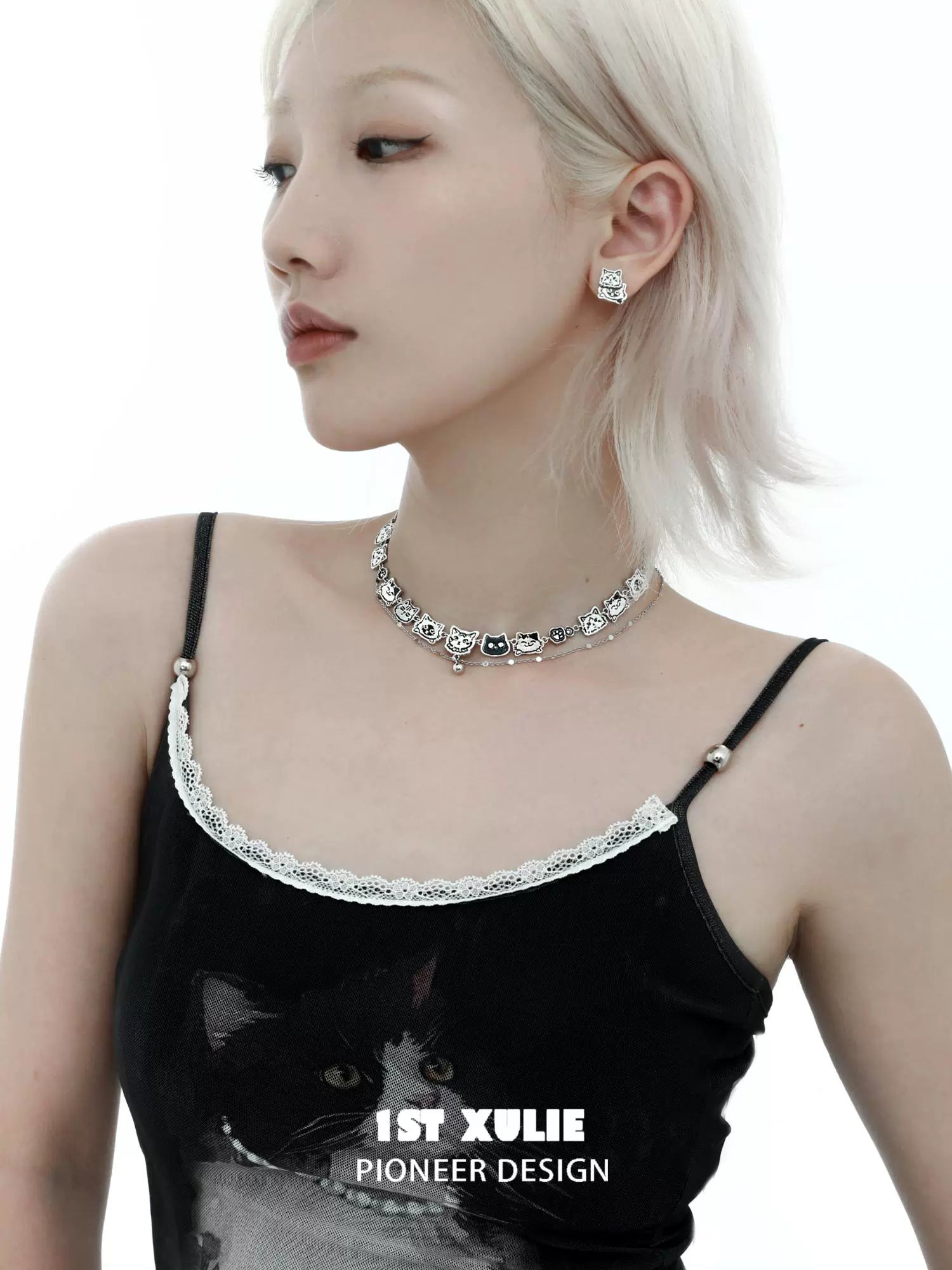 Stylish woman wearing a graffiti cat necklace with matching earrings for trendy accessory lovers