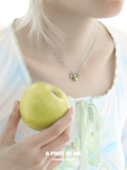 Model wearing a delicate green apple star necklace with a fresh green apple in hand