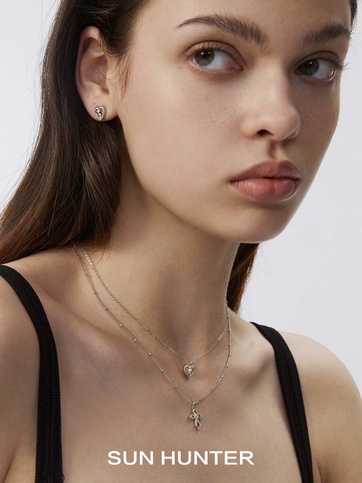 Model wearing heart cross double layer necklace by SUN HUNTER with matching earrings