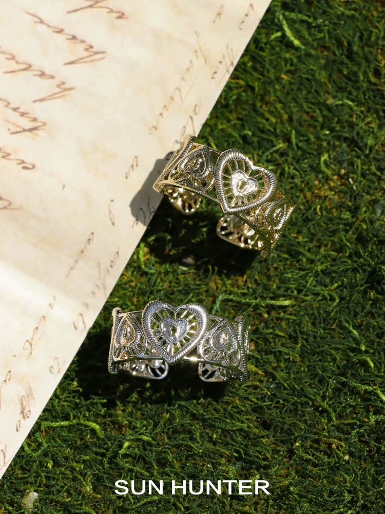 SUN HUNTER heart lock ring set in gold and silver with intricate detailing on a natural background
