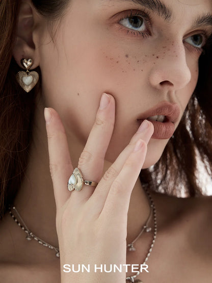 Fashion model wearing SUN HUNTER heart shaped statement earrings with a matching ring and delicate chain necklace