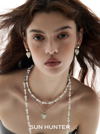 Model wearing heart shaped statement earrings paired with layered pearl necklaces by SUN HUNTER