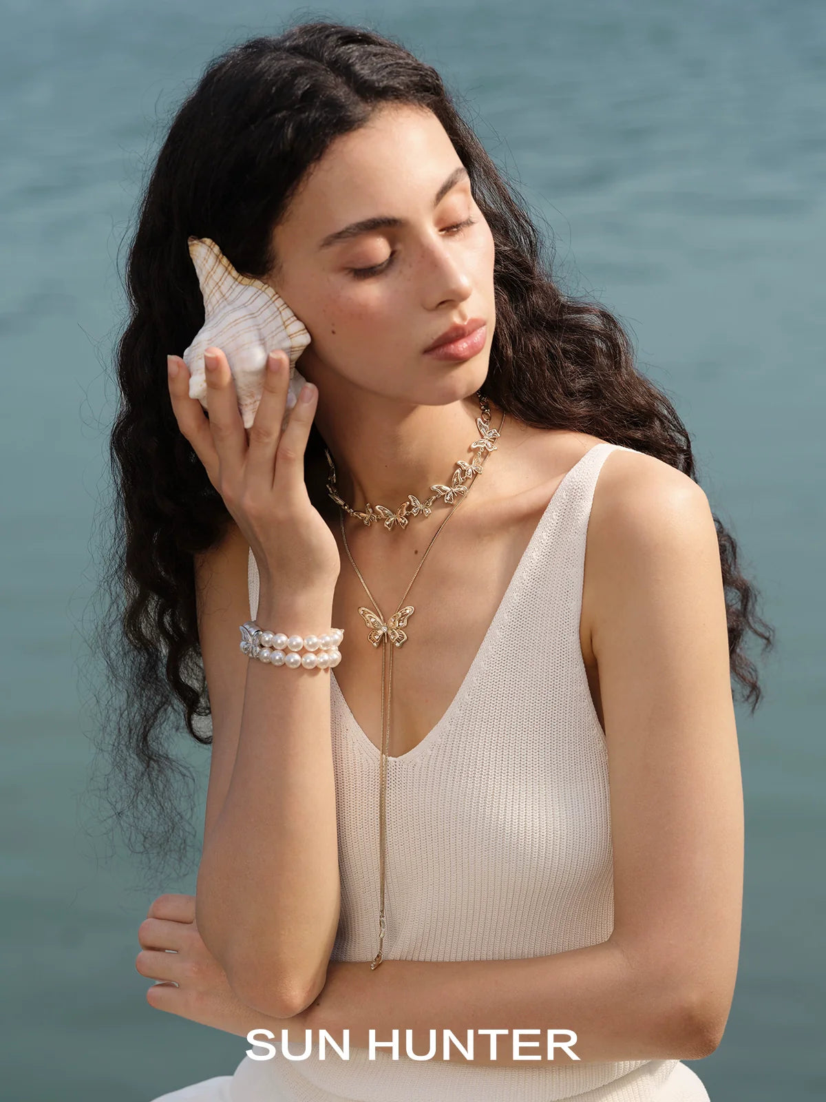 Elegant lace butterfly pearl bracelet from SUN HUNTER worn on model by the water