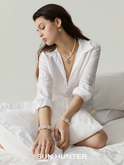 Elegant model wearing lace cross earrings with pearls in a soft, minimalistic setting
