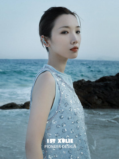 Stylish model wearing mermaid tail ear piercing jewelry by 1STXULIE near the ocean