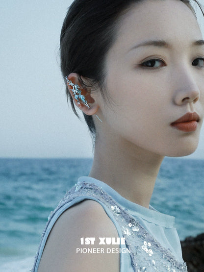 Stunning mermaid tail ear piercing jewelry showcased on model near the ocean for a unique beach look
