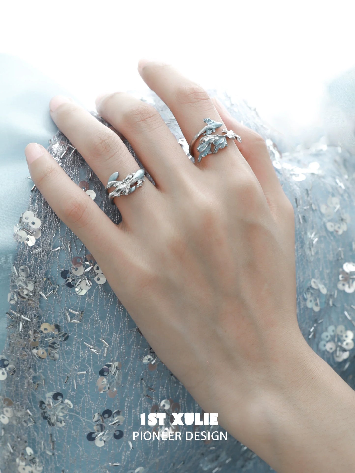 Elegant mermaid tail silver ring on a hand with stunning details and shimmering background