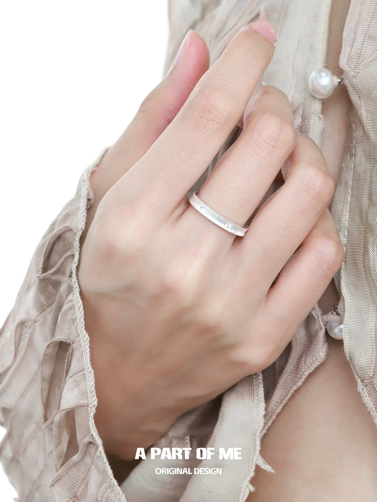 Minimalist silver ring worn on a hand with a stylish blouse for modern elegance