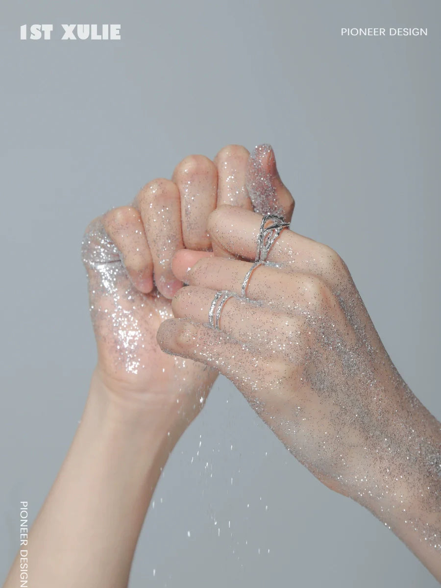 Two hands adorned with minimalist silver rings, sparkling with glitter for a stylish look