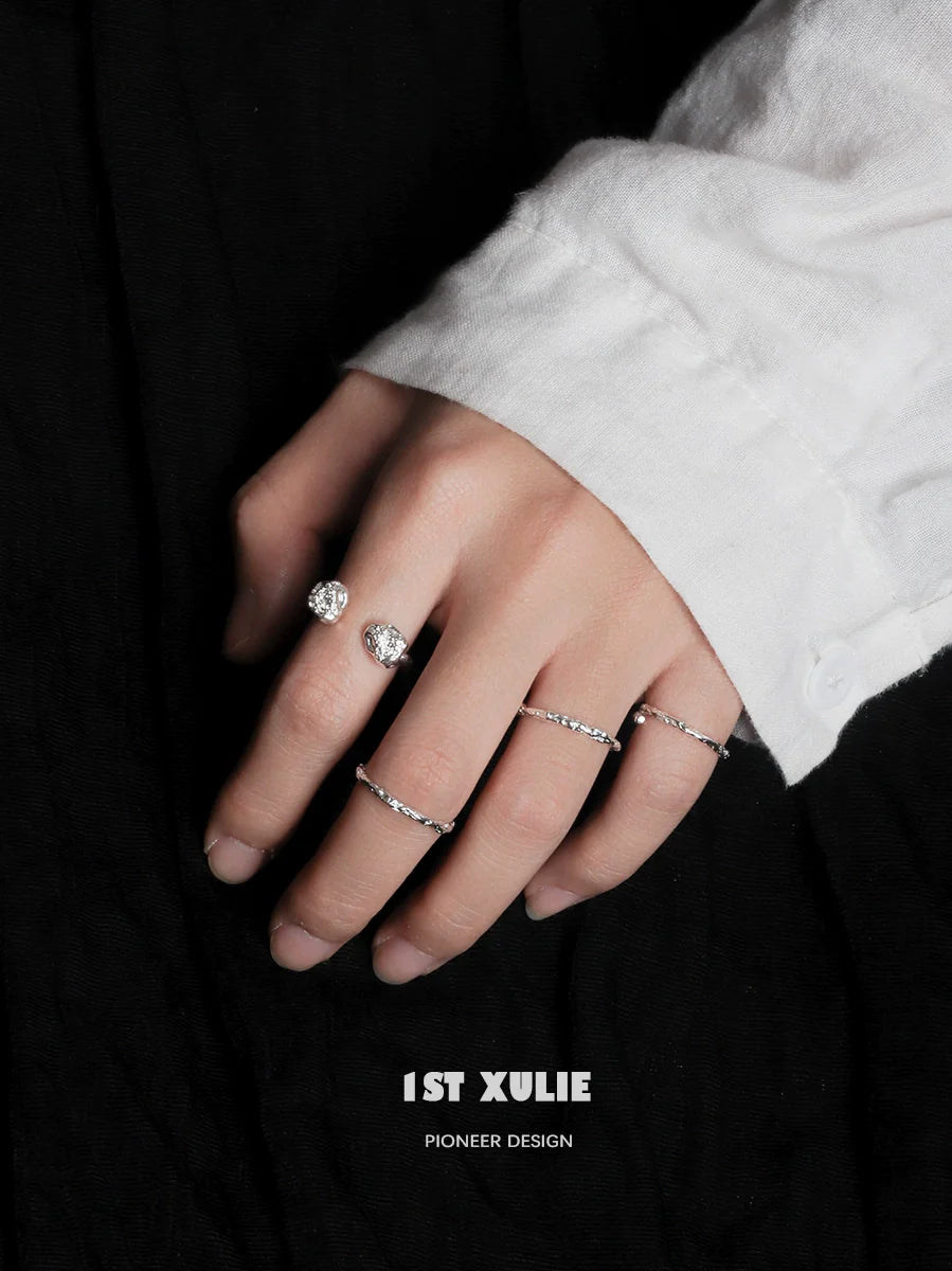 Two minimalist silver rings showcased on a hand with a white shirt, highlighting elegant simplicity
