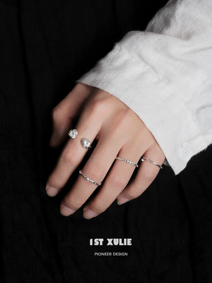 Two minimalist silver rings showcased on a hand with a white shirt, highlighting elegant simplicity