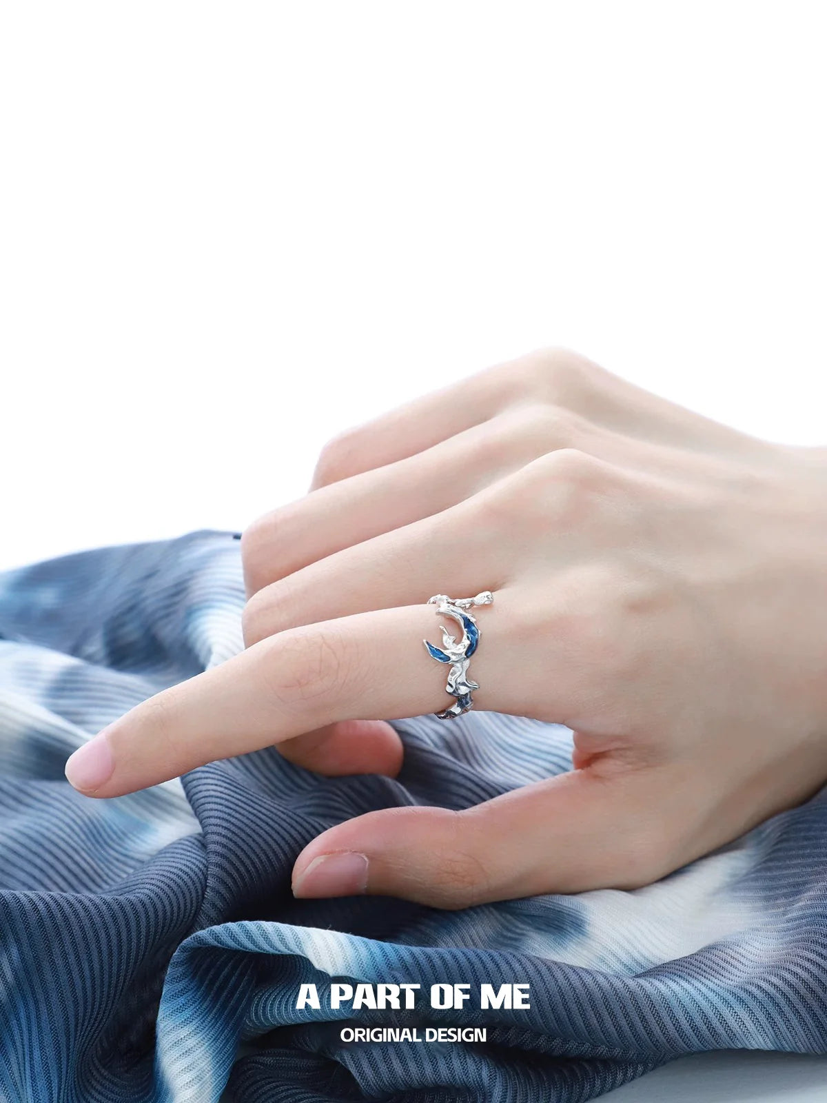 A PART OF ME Mystic Blue Moon Ring elegantly showcased on a model's hand against a blue fabric background