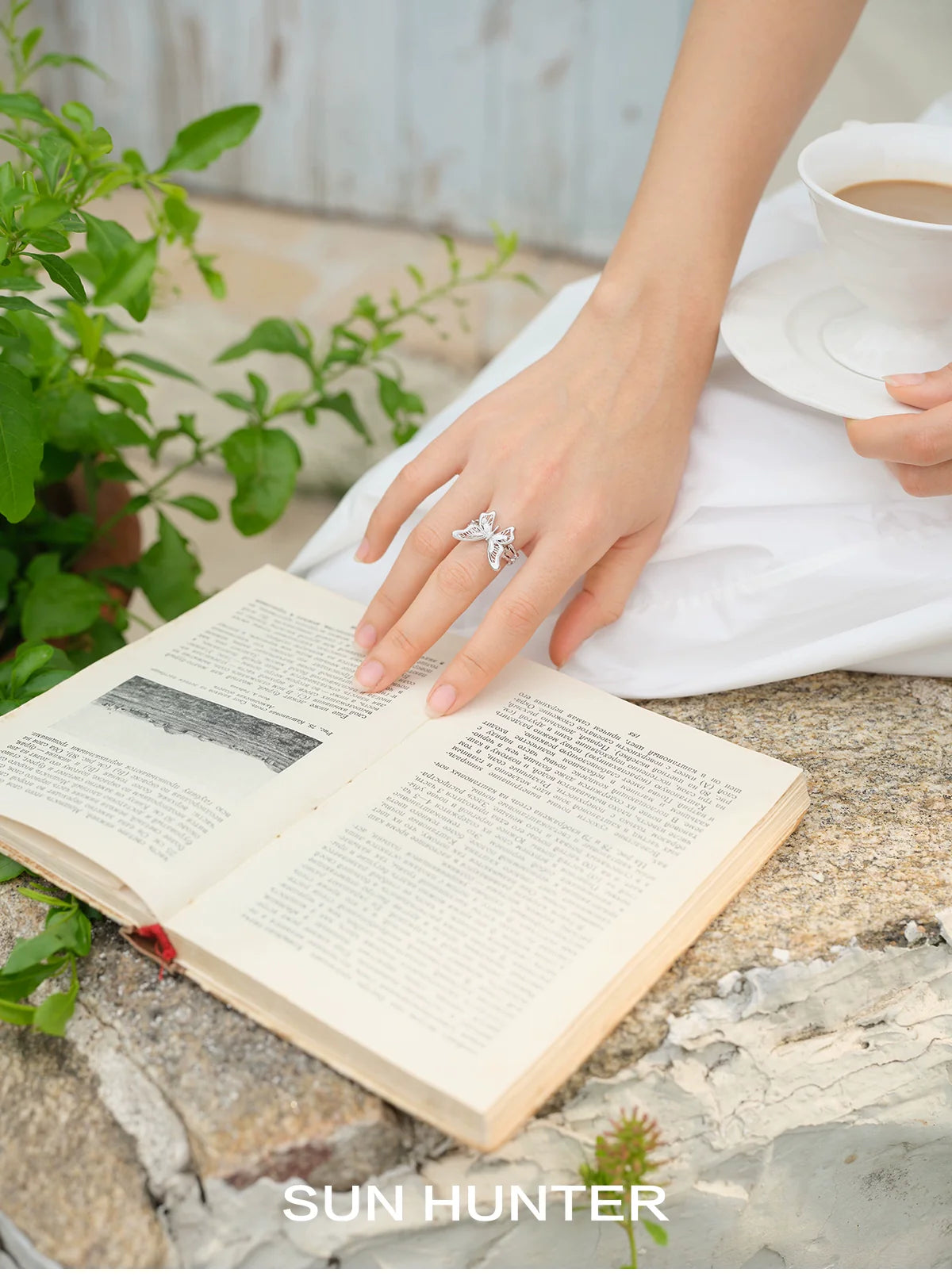 Elegant SUN HUNTER mystic butterfly ring showcased on a hand holding a book while enjoying tea