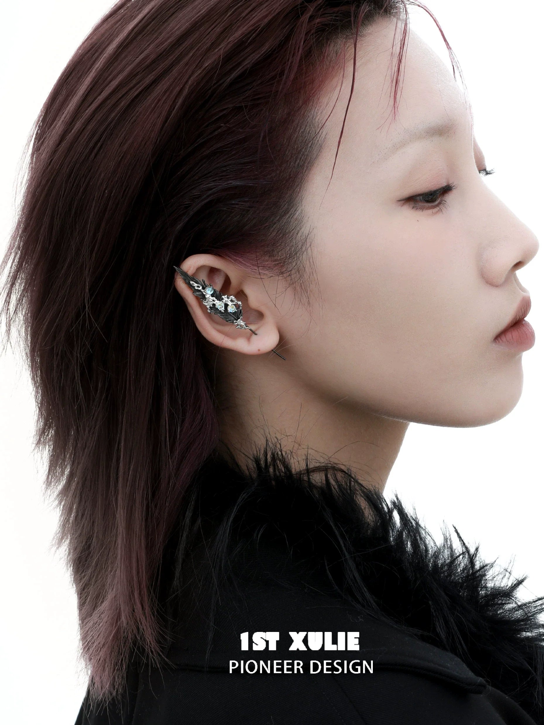 Unique mystic feather piercing earring designed by 1ST XULIE, showcased on a model's ear