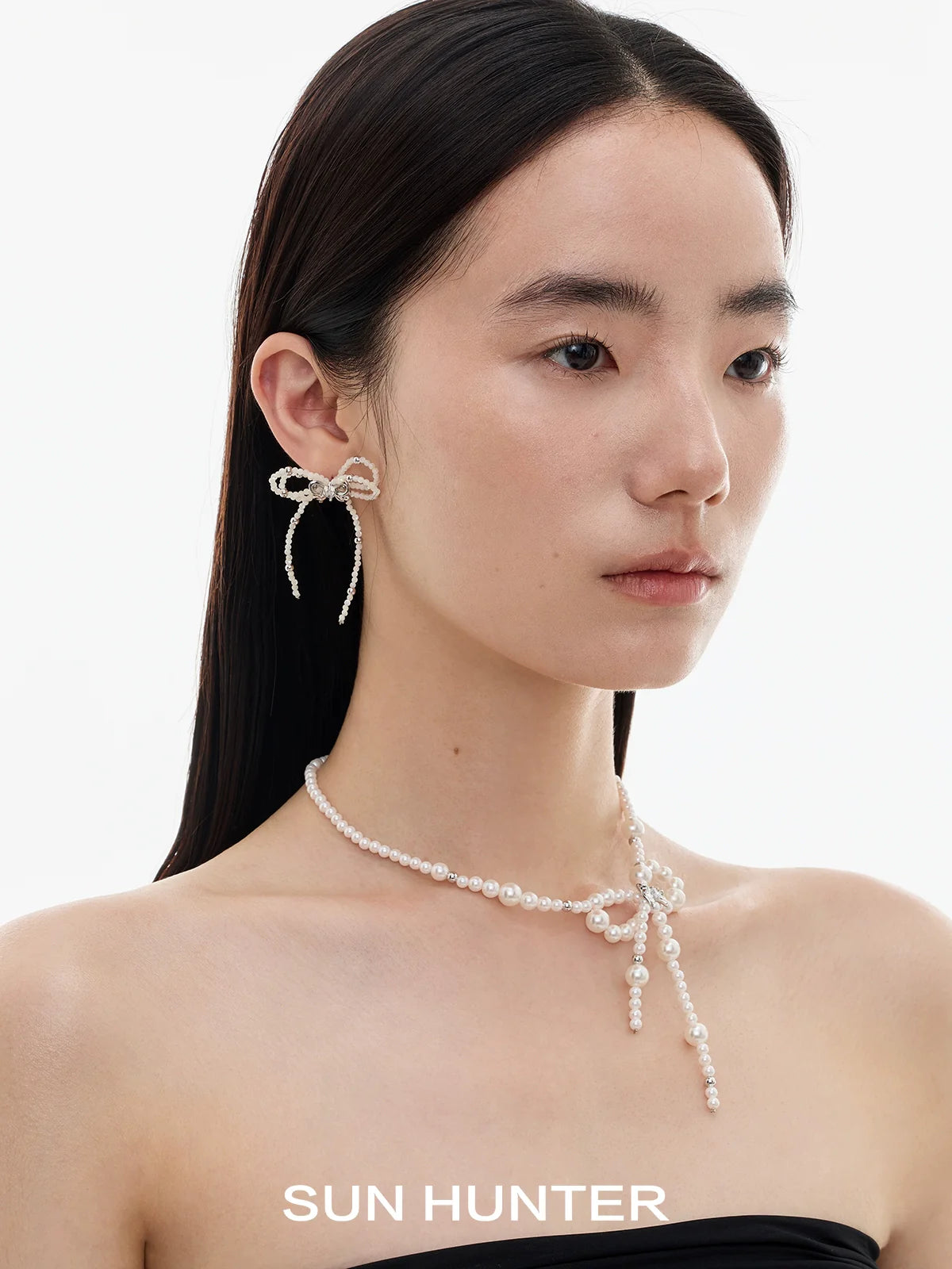 Elegant SUN HUNTER pearl bow ribbon earrings featured on a model showcasing a chic look