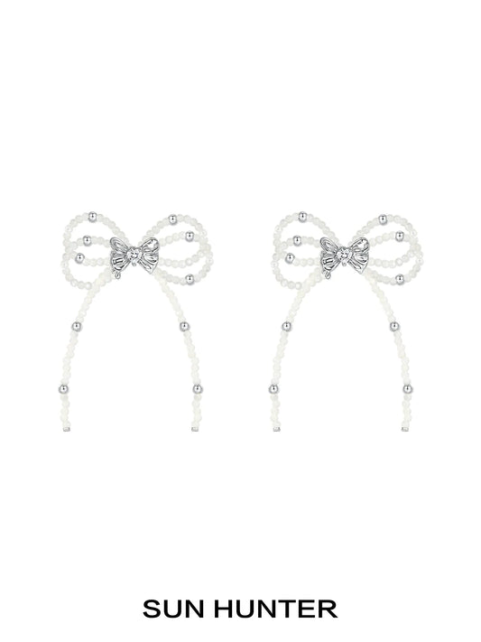 Elegant SUN HUNTER pearl bow ribbon earrings featuring sparkling accents for a stylish look