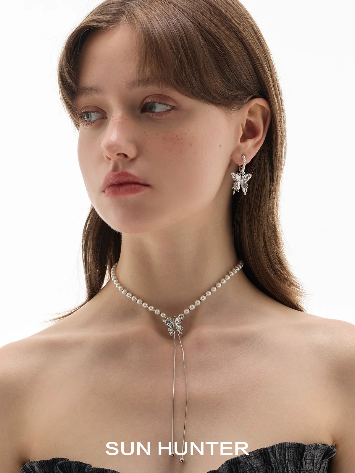 Model wearing pearl butterfly earrings from SUN HUNTER with a pearl choker necklace