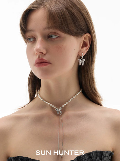 Model wearing pearl butterfly earrings from SUN HUNTER with a pearl choker necklace
