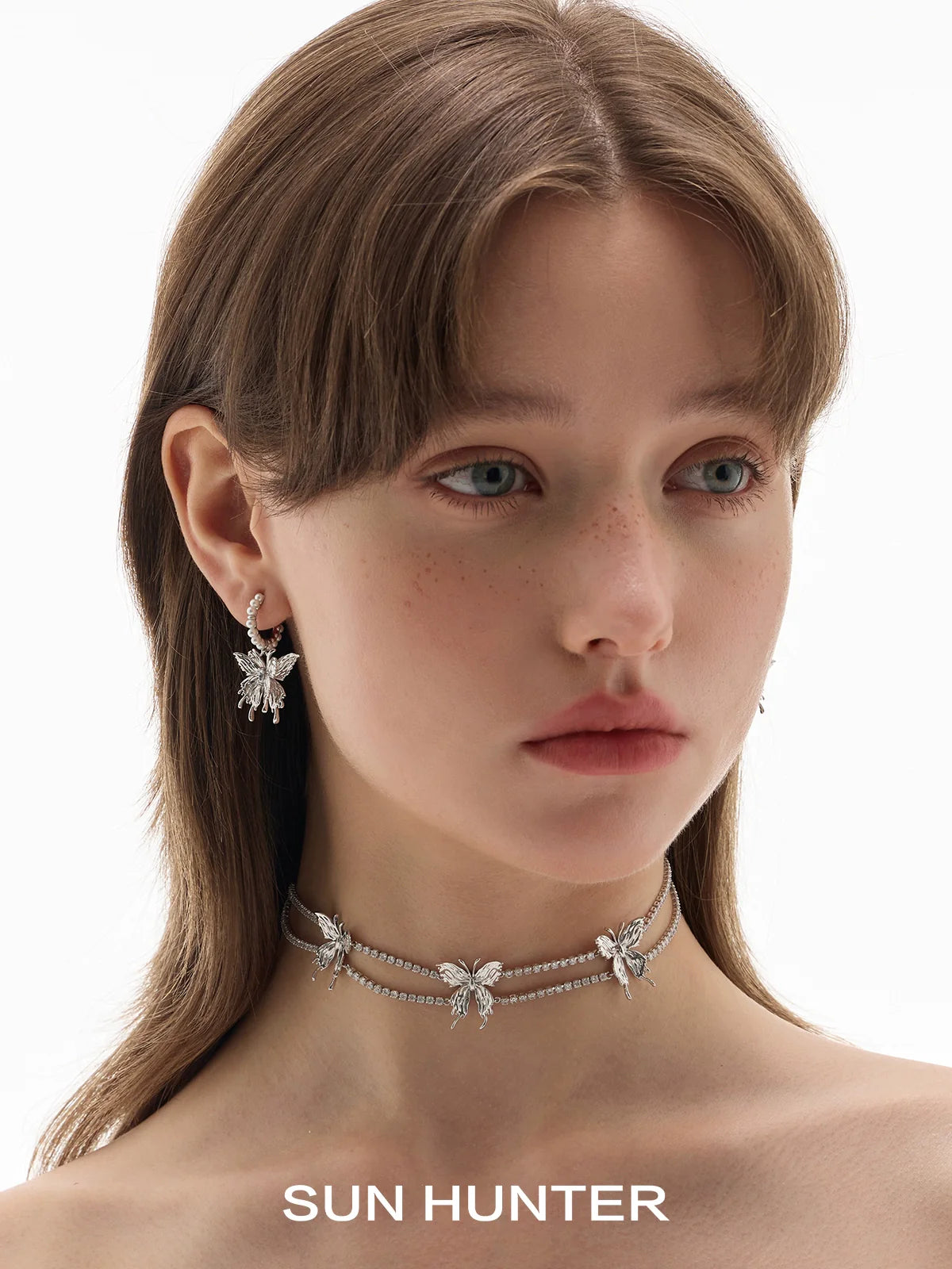 Elegant SUN HUNTER pearl butterfly earrings showcased on a model with a matching choker