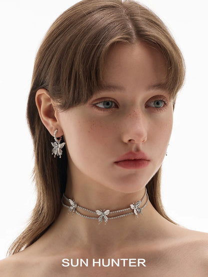 Elegant SUN HUNTER pearl butterfly earrings showcased on a model with a matching choker