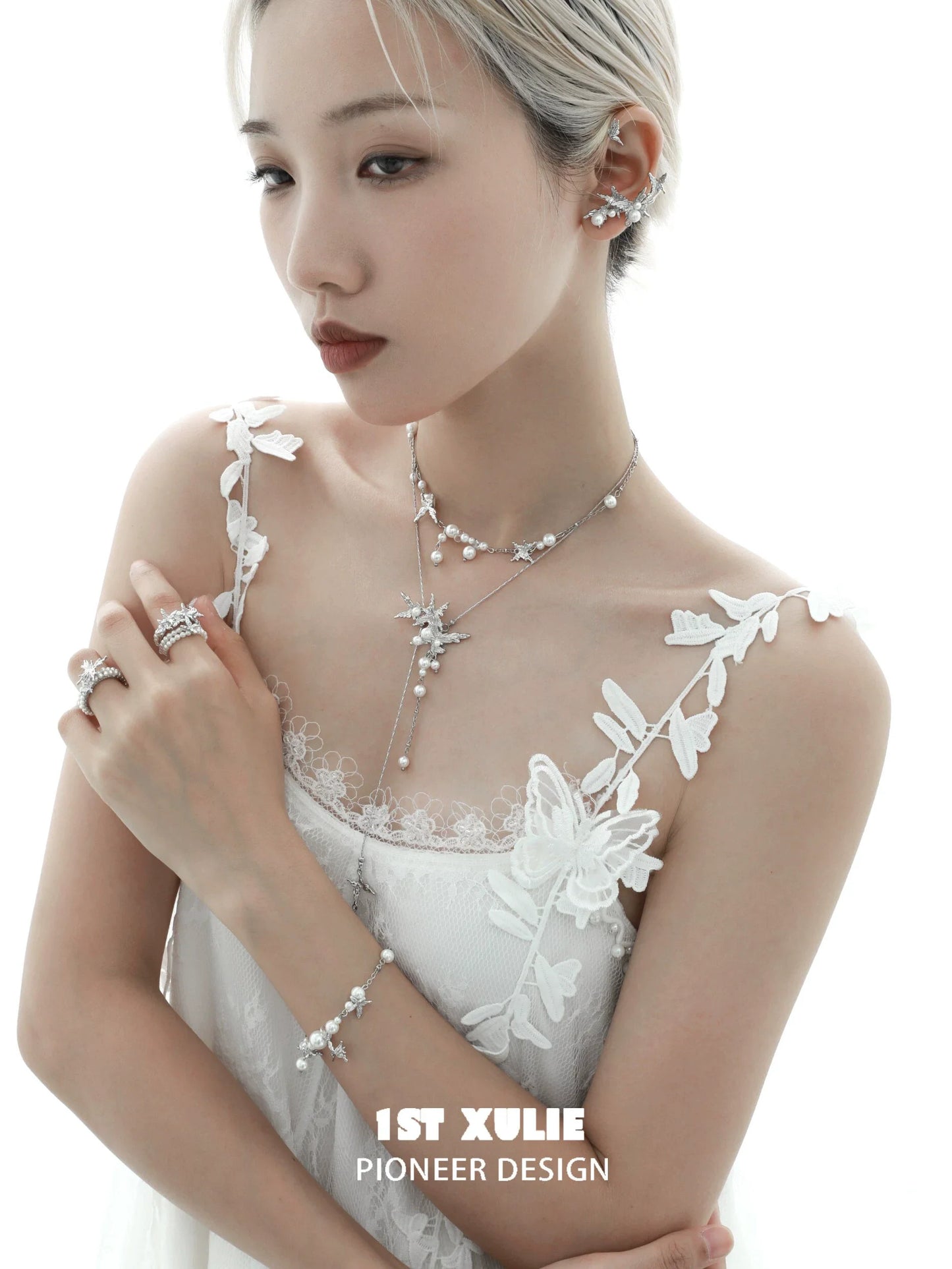 Elegant model wearing a pearl butterfly ring alongside matching jewelry pieces in a soft light