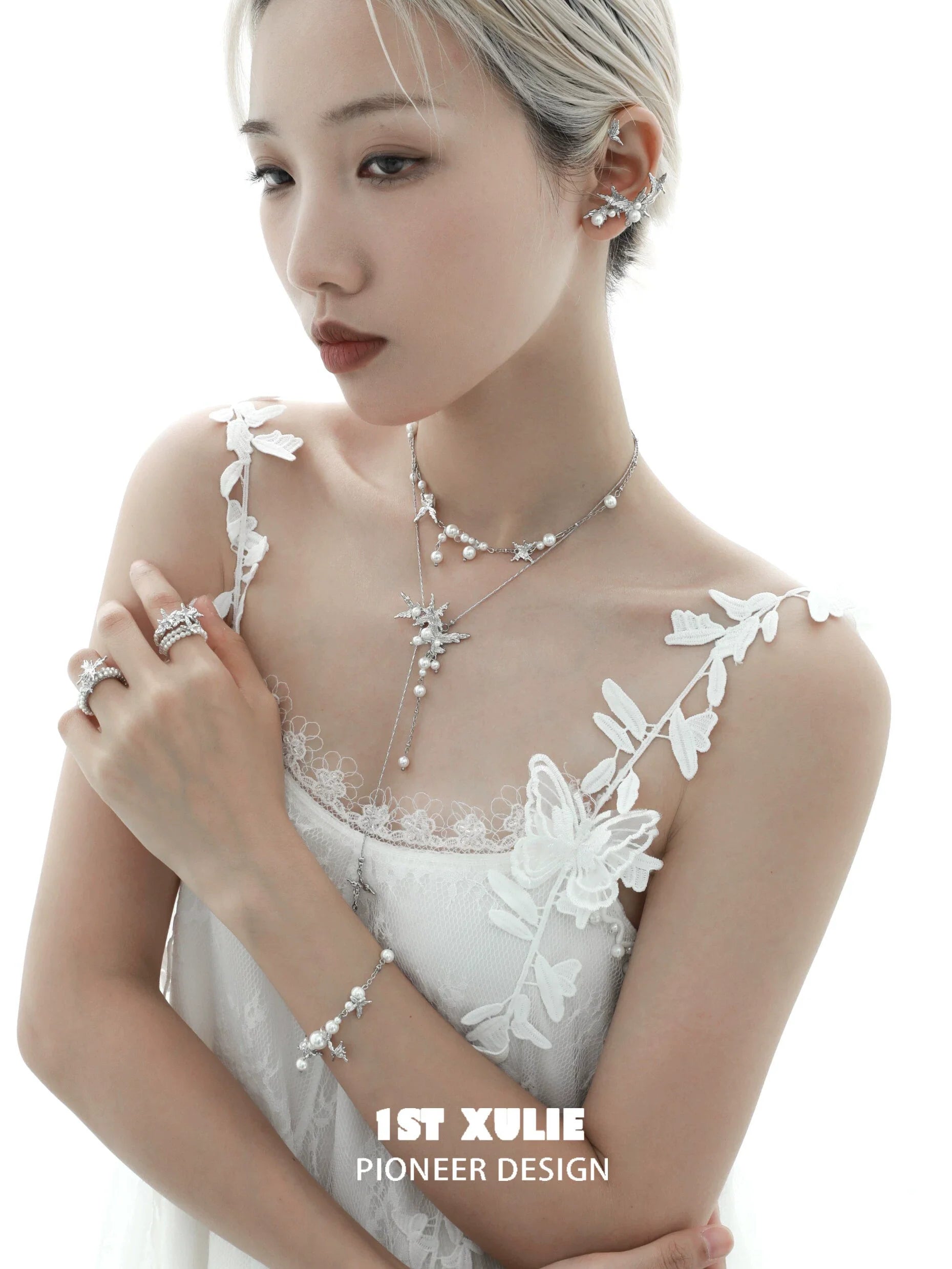 Elegant model wearing a pearl butterfly ring alongside matching jewelry pieces in a soft light