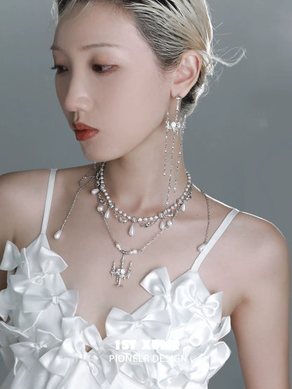 Elegant pearl clavicle necklace layered with silver accents, styled on a model wearing a white outfit