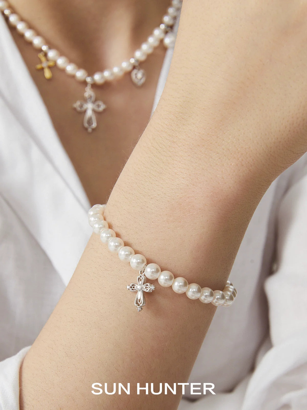 Elegant pearl cross bracelet by SUN HUNTER featuring a delicate cross charm and lustrous pearls