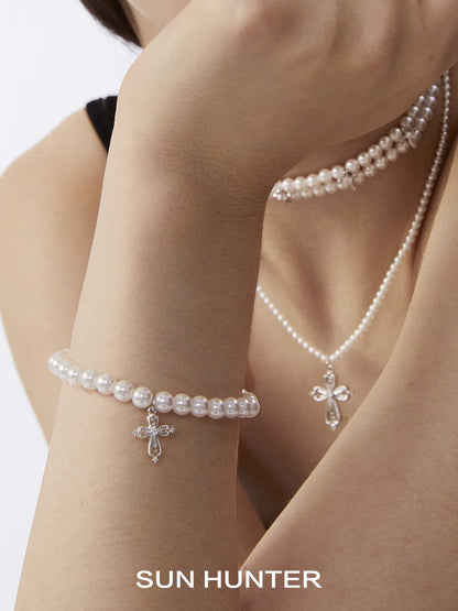 Elegant SUN HUNTER pearl cross bracelet featuring sparkling cross pendant and classic pearl design