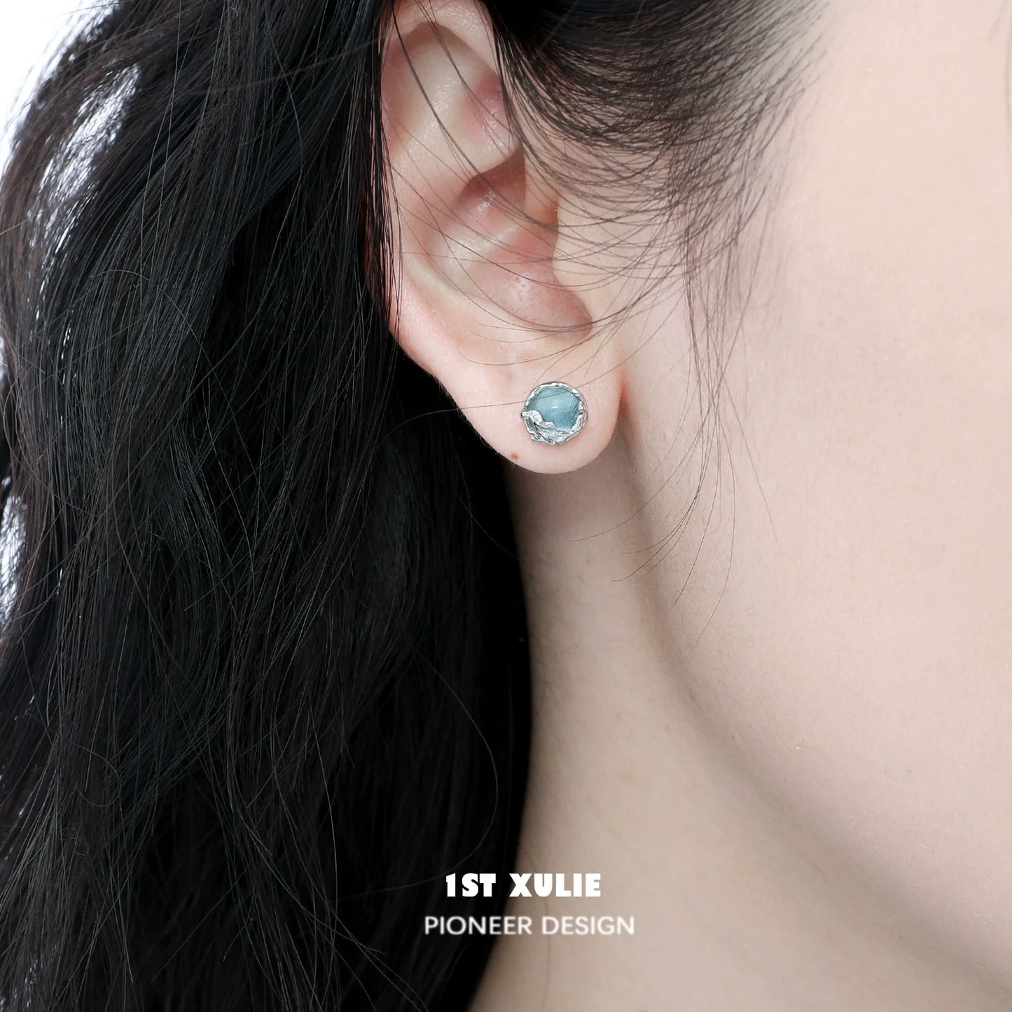 Elegant aqua gemstone stud earrings displayed on a model's ear with dark hair