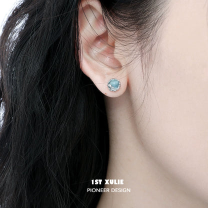Elegant aqua gemstone stud earrings displayed on a model's ear with dark hair