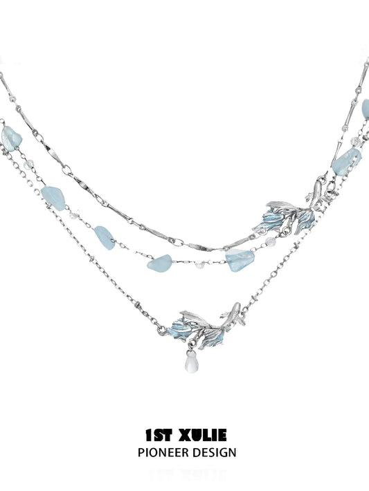 Elegant playful fish necklace with layered silver chains and blue gemstones for a whimsical touch