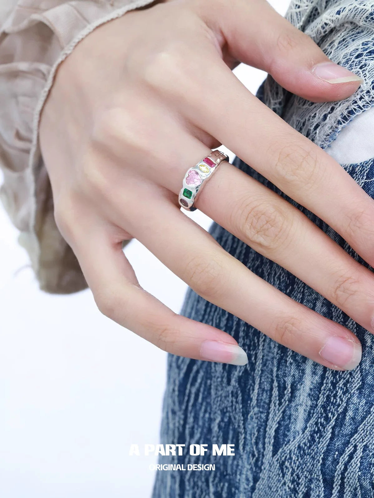 A stylish rainbow zircon love ring featured on a hand with long nails, perfect for romantic occasions