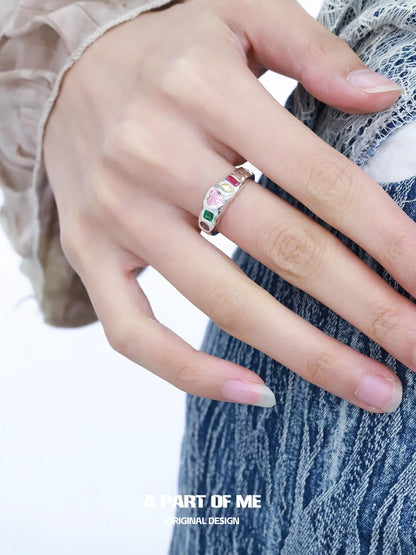A stylish rainbow zircon love ring featured on a hand with long nails, perfect for romantic occasions