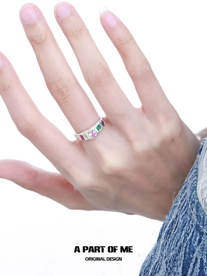 Silver rainbow zircon love ring displayed on a hand with colorful gemstones for a vibrant look