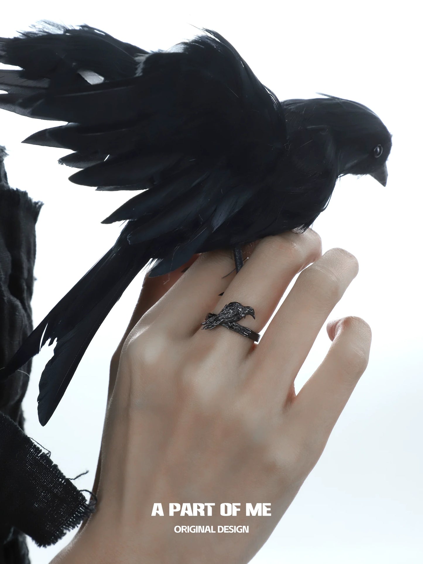 A PART OF ME raven gothic ring worn on a hand with a black bird perched on it