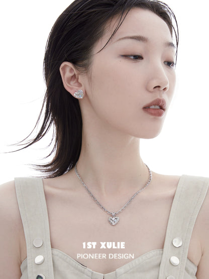 Model wearing a removable clavicle chain necklace with a heart pendant and matching earrings