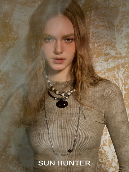 Model wearing retro metal water drop earrings by SUN HUNTER with layered necklaces and a textured top