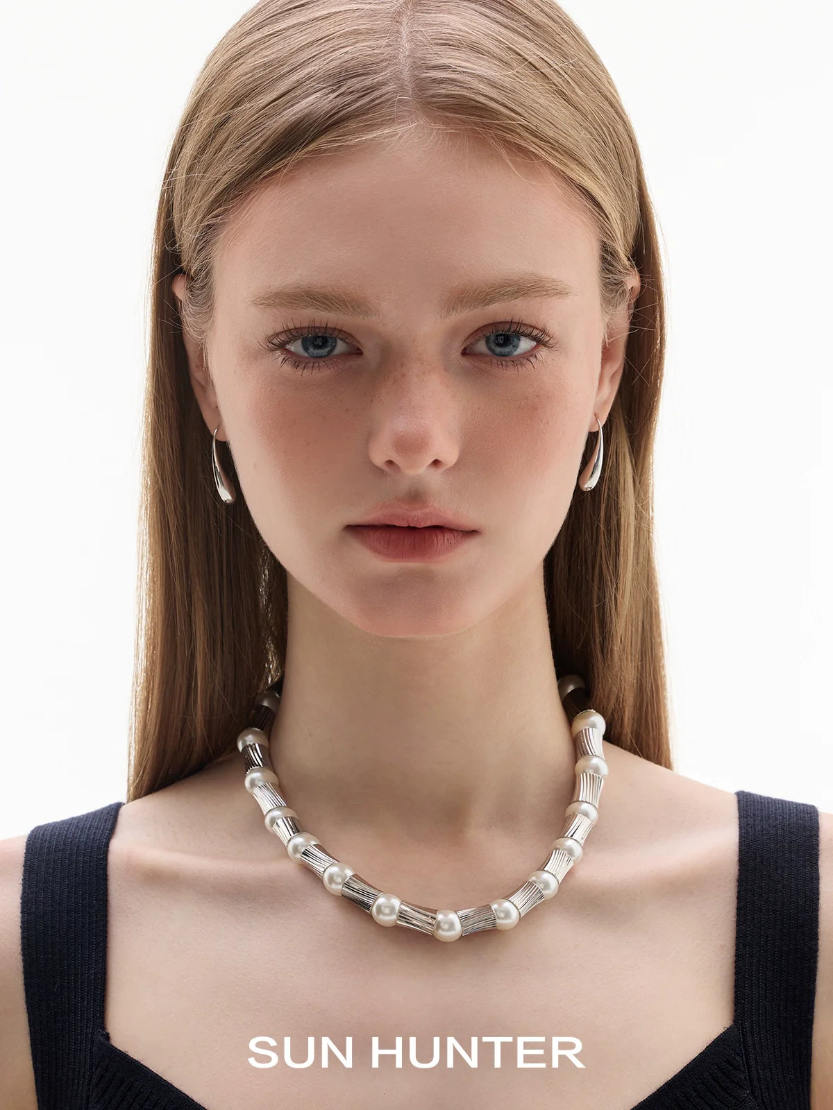 Model wearing SUN HUNTER retro metal water drop earrings with a pearl necklace, showcasing a stylish look
