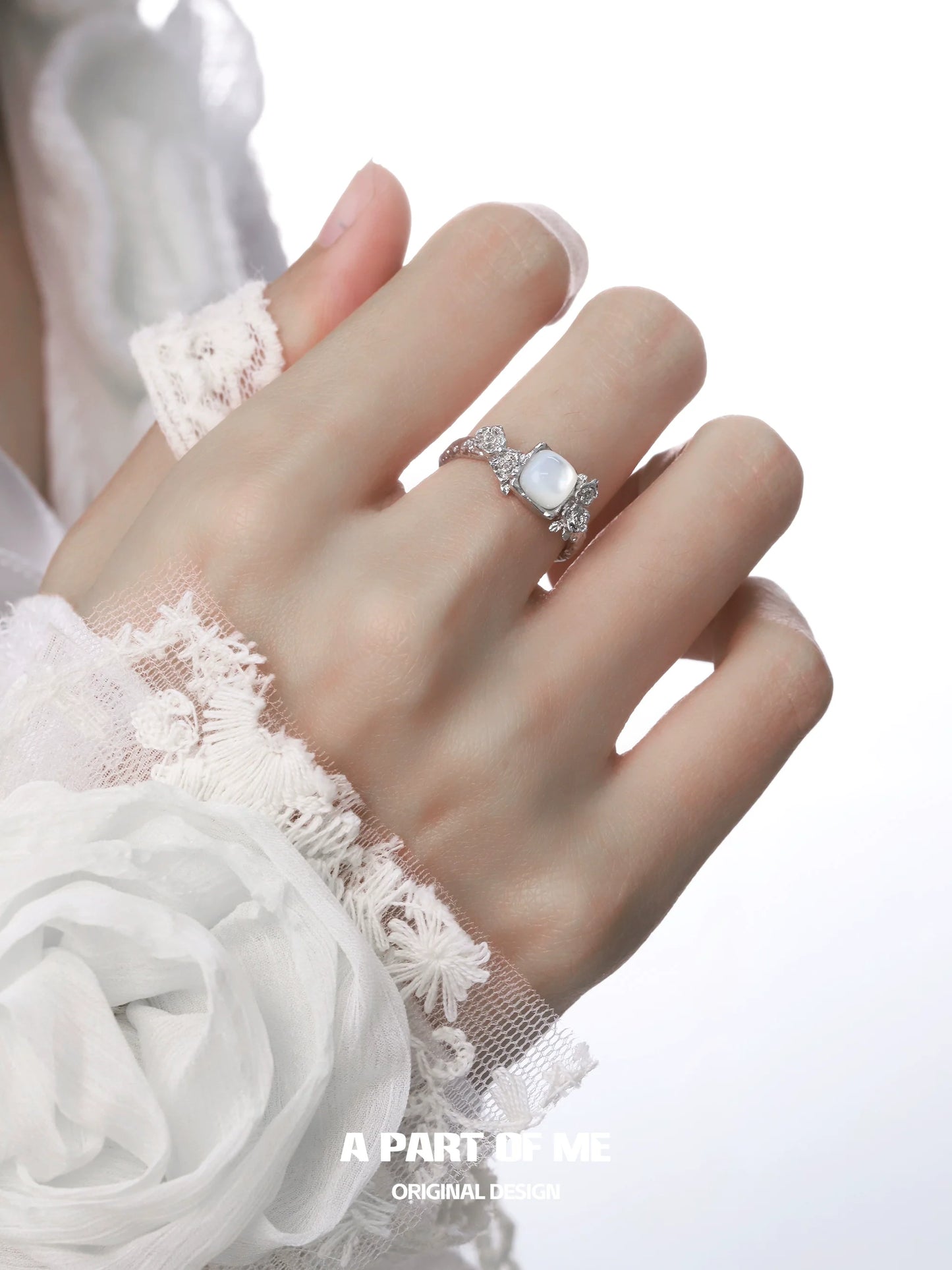 Elegant rose silver ring with intricate design worn on a hand adorned in lace