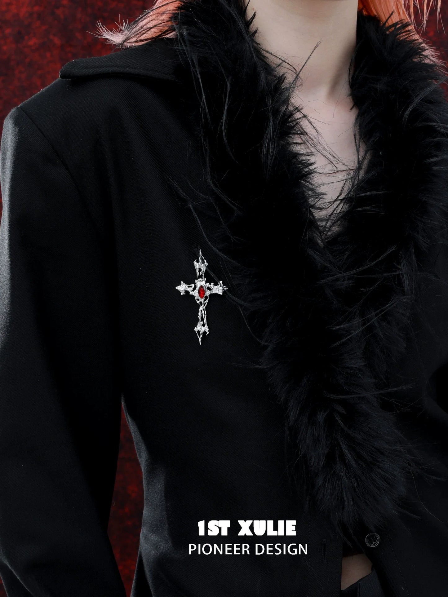 Elegant sacred cross silver brooch adorned with red gem on a black jacket with feather trim