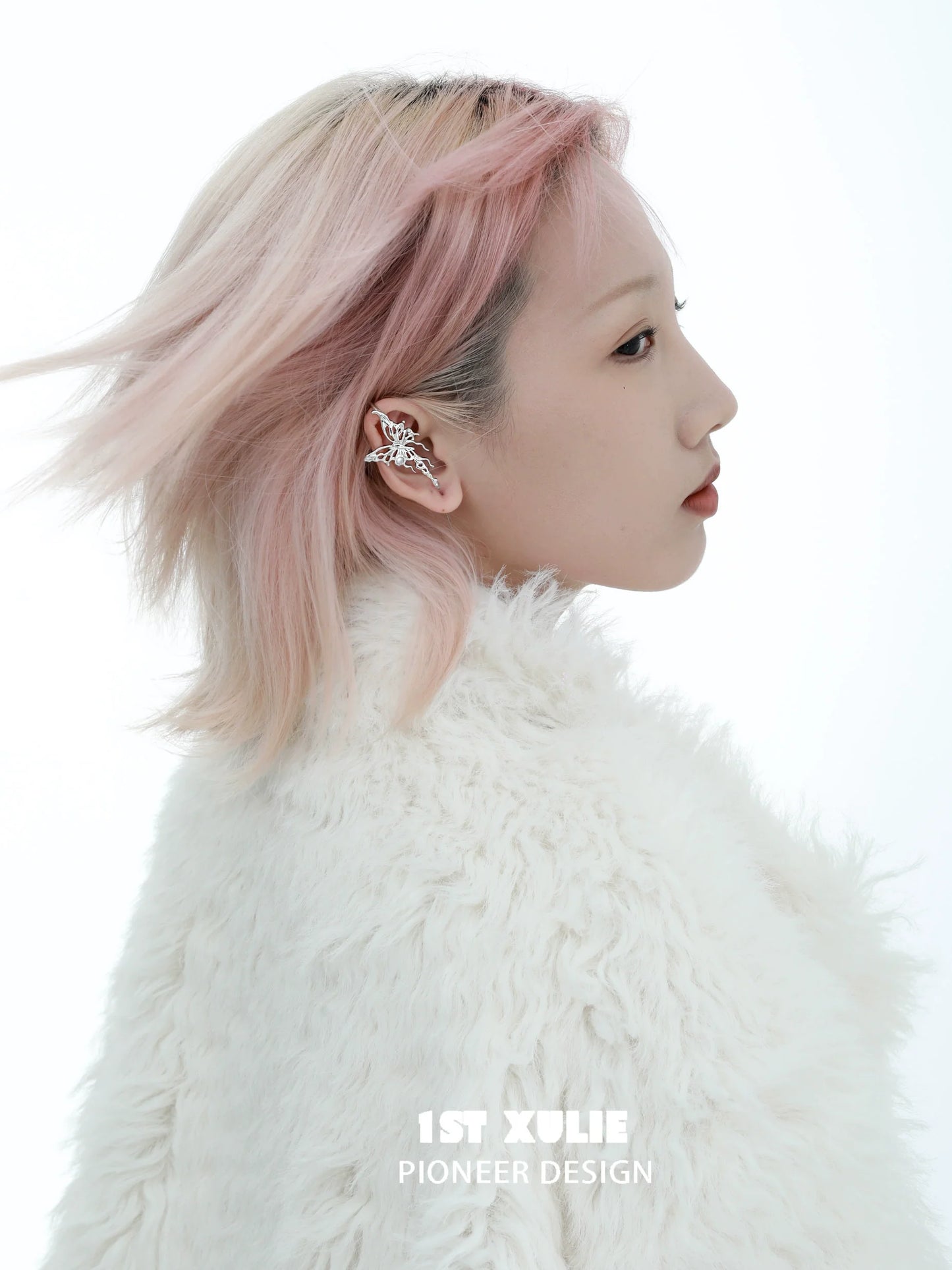 Model showcasing a silver butterfly piercing earring, styled with a fluffy white coat and soft pink hair