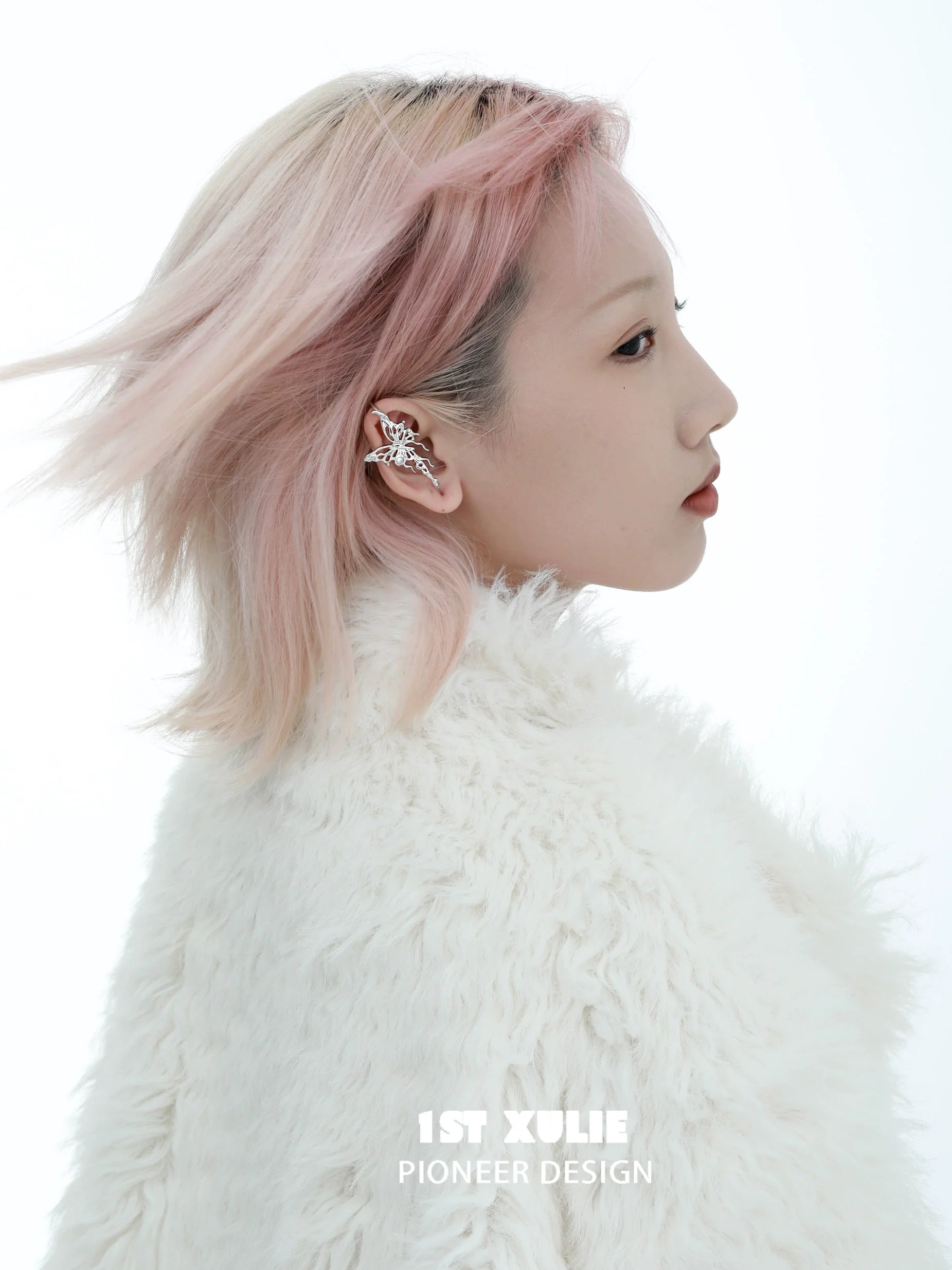 Model showcasing a silver butterfly piercing earring, styled with a fluffy white coat and soft pink hair