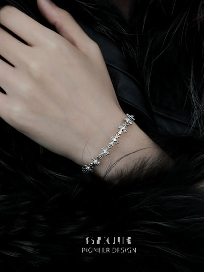 Elegant silver cross bracelet delicately worn on a hand against a dark fur background