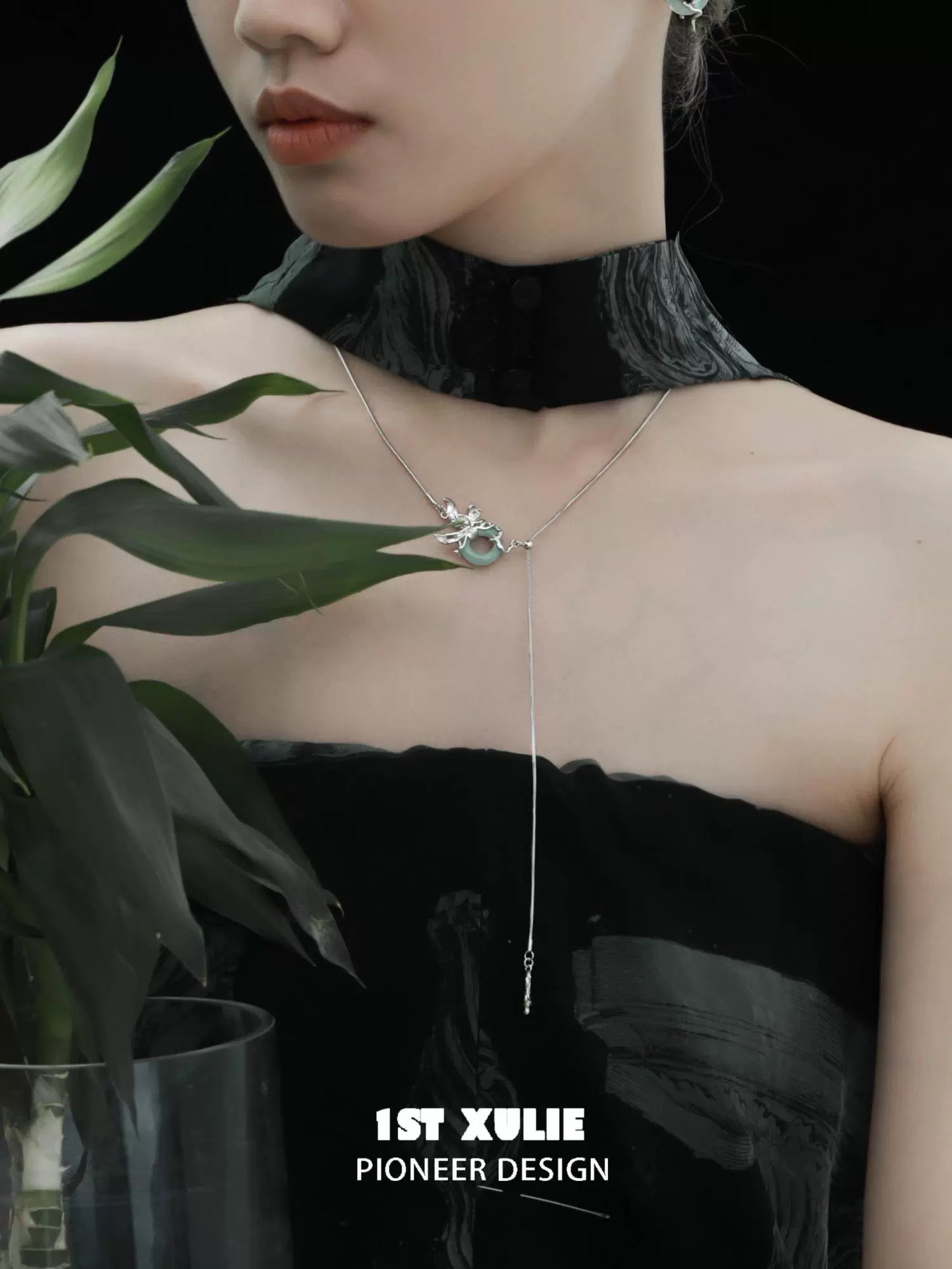 Stylish silver iris pull buckle necklace featuring floral design worn by a model with plant backdrop