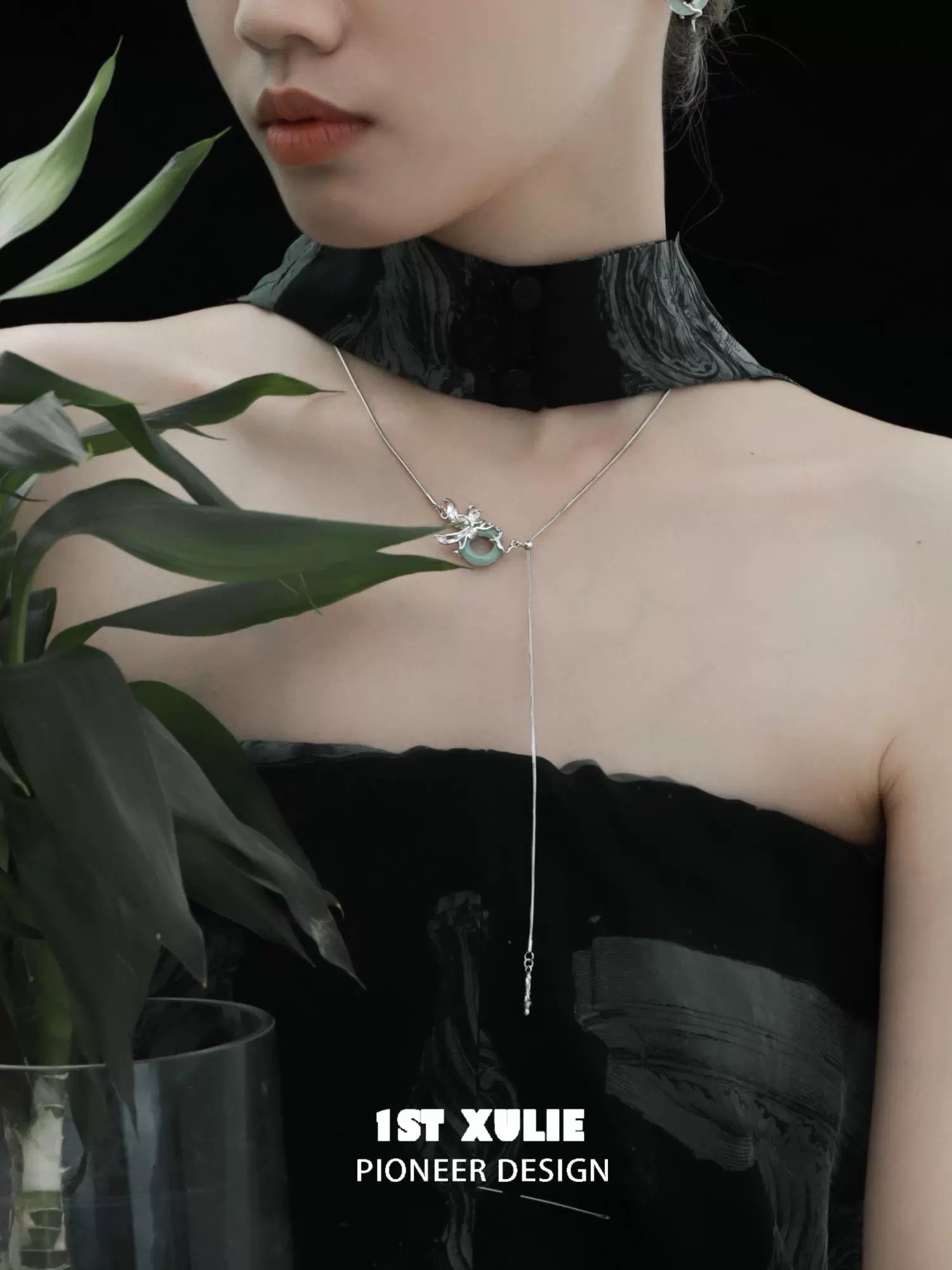 Stylish silver iris pull buckle necklace featuring floral design worn by a model with plant backdrop